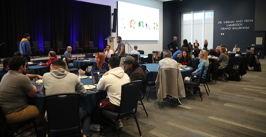 Depicted are groups of people sitting at tabled and talking at UC Merced's Merced 2 Market event.